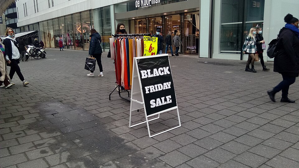 路上に置かれた「BLACK FRIDAY SALE」と書かれた黒い立て看板と、その奥の衣料品のラック