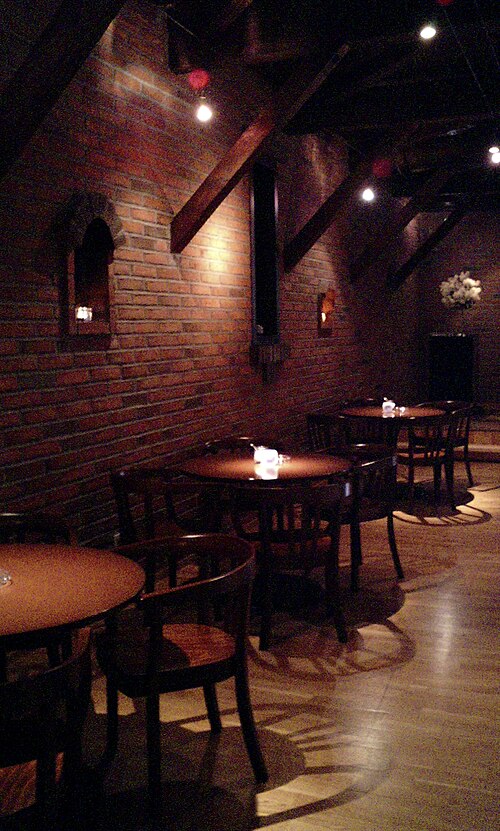 小樽のジャズカフェ。レンガの壁と木の梁、灯りの落ちたテーブル席