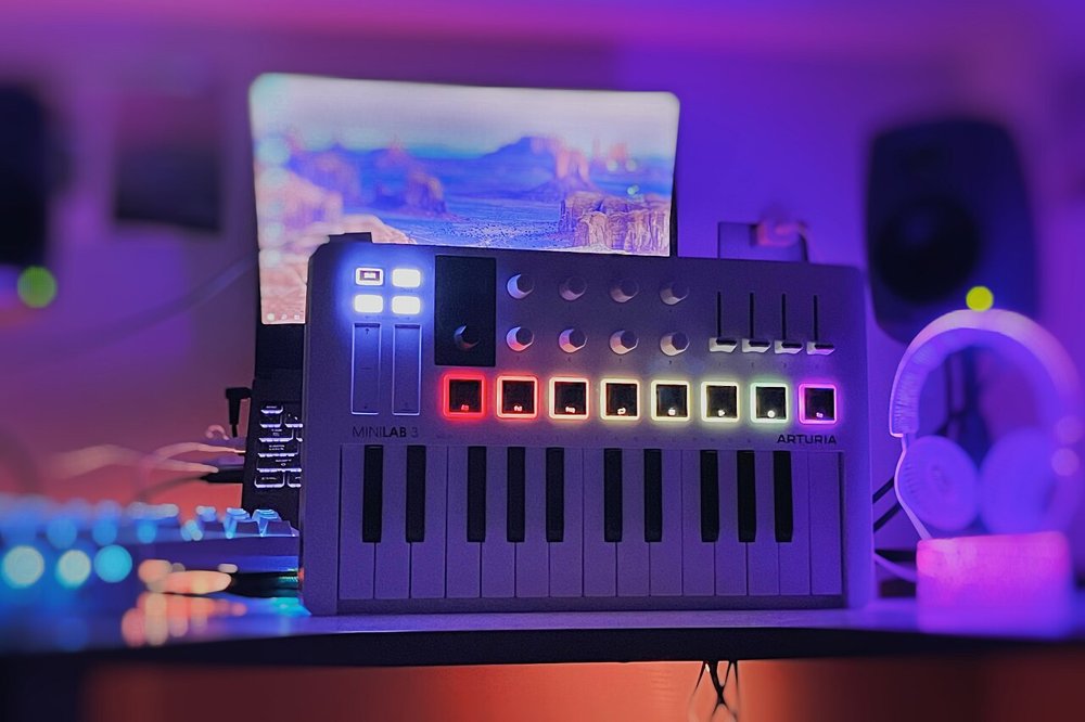 ノートパソコンの前に置かれたArturia MiniLab 3。8つのパッドが色とりどりに光っている