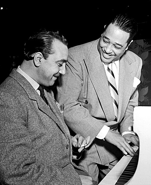 ピアノに向かうジャンゴ・ラインハルトと、ストライプタイにスーツ姿のデューク・エリントン（1946年）