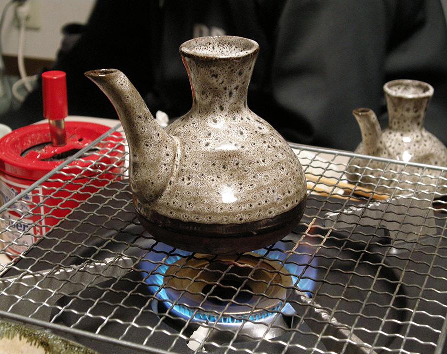 ガスの火にかけた網の上で温められる燗徳利
